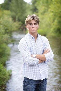 a man standing in front of a river with his arms crossed