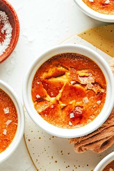 three white bowls filled with soup on top of a table