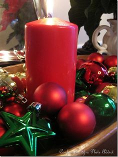 a red candle surrounded by christmas ornaments