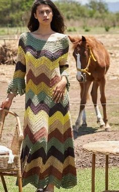 a woman standing next to a brown horse on top of a grass covered field with a basket