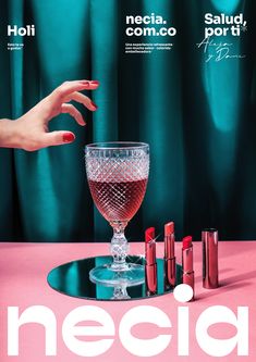 a woman's hand reaching into a wine glass with lipstick on the table next to it