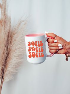 a woman holding a coffee mug with the words sofie sole on it and an orange print