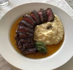 a white plate topped with meat and mashed potatoes