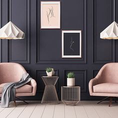 a living room with two chairs, a table and pictures on the wall behind them