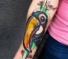 a woman's arm with a colorful bird tattoo on the left side of her right arm