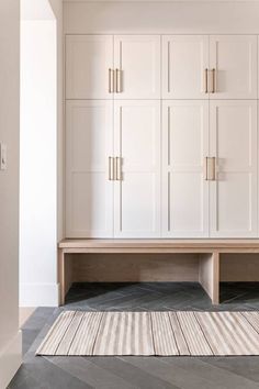 an empty room with white cabinets and rugs on the floor in front of it