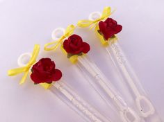 four plastic roses with yellow ribbon on them sitting next to each other in front of a white background