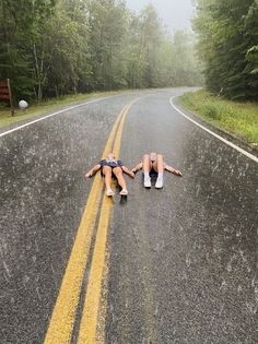 two people laying down on the side of a road