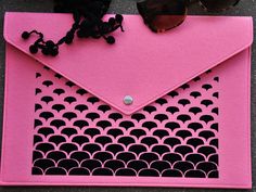 a pink envelope with black and white fish scales on it, next to some sunglasses