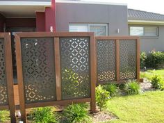 a fence in front of a house with grass and bushes on the side of it