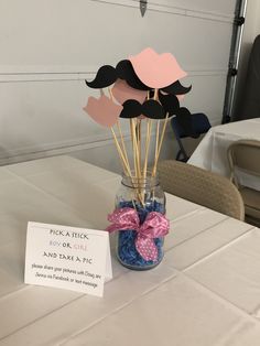 a vase filled with fake mustaches and pink bow on top of a white table