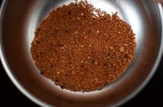 a metal bowl filled with spices on top of a table