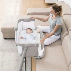 a woman sitting on the floor next to a couch with a baby in her lap