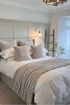 a bed with white linens and pillows in a bedroom next to a large window