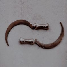 two metal hooks on the side of a white wall, one has an open end