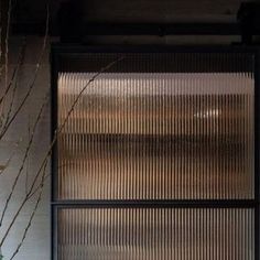 a vase with some flowers in it next to a glass door that has blinds on it