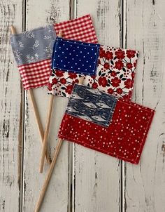 three small red, white and blue patchwork flags on toothpicks next to each other