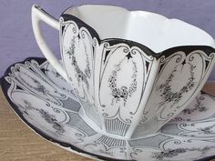 a cup and saucer sitting on top of a wooden table next to a purple wall