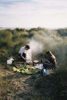 two people sitting on the ground cooking food