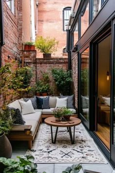 an outdoor living area with couches, tables and potted plants on the floor