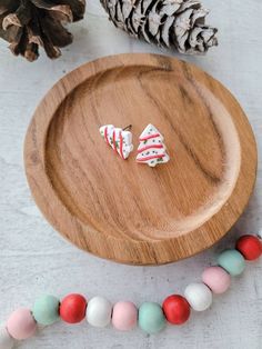 wooden plate with christmas decorations on it next to pine cones and candy canes in the foreground