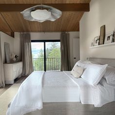 a large bed in a bedroom next to a sliding glass door that leads out onto a balcony