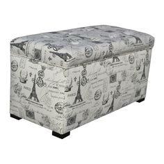 an upholstered storage ottoman with blue and white paris images on the fabric, sitting in front of a white background