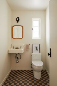 a white toilet sitting next to a sink in a bathroom under a mirror and a window