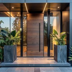 the entrance to a modern home with two large planters