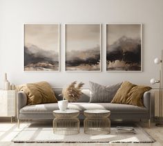 a living room with three paintings on the wall and two couches in front of it