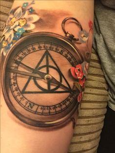 a woman with a tattoo on her arm has a compass and flowers around the wrist