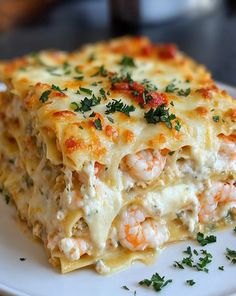 a white plate topped with lasagna covered in shrimp and cheese sauce, garnished with parsley