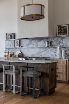 a kitchen with marble counter tops and stools next to an island in the middle