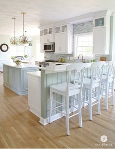 a kitchen with an island and white chairs