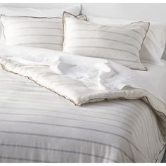 an unmade bed with white sheets and pillows