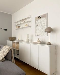 a living room filled with furniture and a large white cabinet next to a couch on top of a hard wood floor