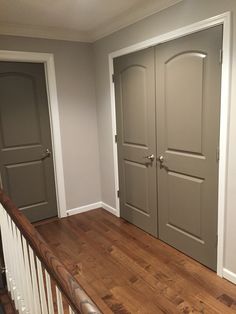 an empty room with two doors on the wall and wood flooring in front of it