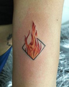 a tattoo on the arm of a woman with a red fire in her center and writing underneath it