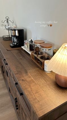 a wooden counter top sitting next to a lamp and coffee maker in a living room