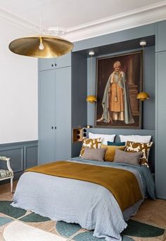 a bedroom with blue walls and gold bedding in front of a painting on the wall