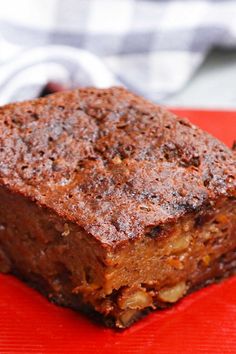 a piece of brownie sitting on top of a red plate next to a fork