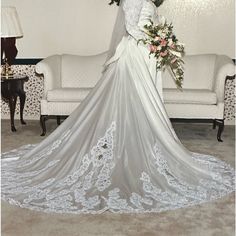 a woman in a white wedding dress standing next to a couch with flowers on it