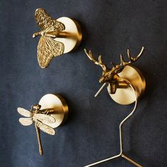 two brass dragonflys are mounted on the wall next to each other, one is holding a hook