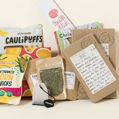 an assortment of teas and snacks on a table with papers, tags, and envelopes