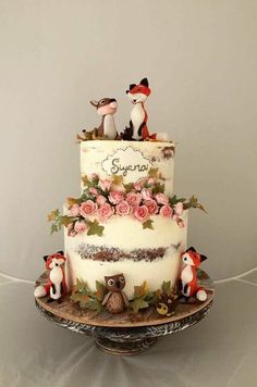 a three tiered cake decorated with figurines and flowers on a platter