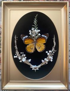 a yellow butterfly sitting on top of a black circle with white flowers and leaves around it