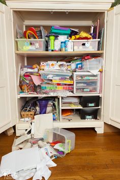 a closet filled with lots of clutter next to a wooden floor and white cupboards