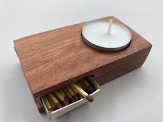 an open matchbox with matches in it and a lit candle on the top one