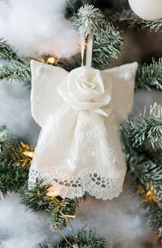 a white ornament hanging from the top of a christmas tree with snow on it