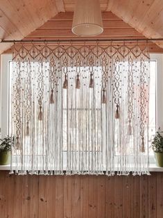 a window with sheer curtains and potted plants